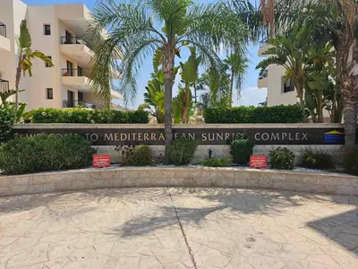 a sign in front of a building with palm trees at Mediterranean Sunrise Apartments A1 in Voroklini