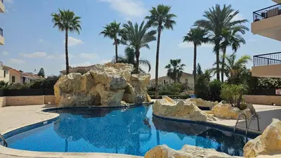 a swimming pool in a resort with rocks and palm trees at Mediterranean Sunrise Apartments A1 in Voroklini