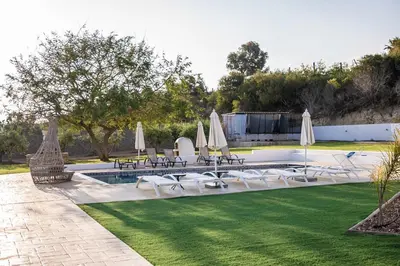 a pool with chairs and umbrellas on a lawn at Konnos Villa 1 in Protaras