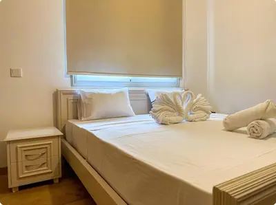 a bedroom with two beds with white sheets and a window at Neptune Apartment in Larnaka