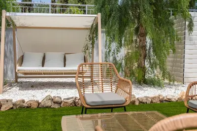 a rattan chair and a bench in a yard at Luxury Seaview Limassol Villa Pool Jacuzzi Sauna in Limassol