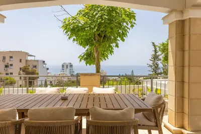 a patio with a wooden table and chairs on a balcony at Luxury Seaview Limassol Villa Pool Jacuzzi Sauna in Limassol