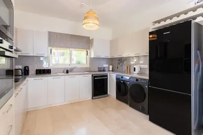 a kitchen with white cabinets and black appliances at Luxury Seaview Limassol Villa Pool Jacuzzi Sauna in Limassol