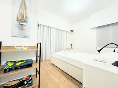 a white bedroom with a large bed and a window at Modern apartment near McKenzie beach in Larnaka
