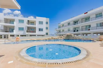 a large swimming pool in front of a building at Stylish One-Bedroom Sea Retreat in Paralimni