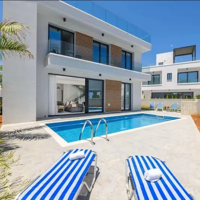 a villa with a swimming pool in front of a house at By the beach Villa 2 in Protaras