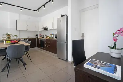 a kitchen with a table and chairs and a refrigerator at Alessia 2bed Apartment - Coralli Beachfront Resort in Protaras