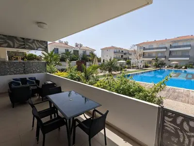 a balcony with a table and chairs and a swimming pool at Violetta Apartment, Ground Floor Pool View in Paralimni