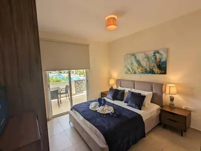 a bedroom with a bed and a table and a window at Violetta Apartment, Ground Floor Pool View in Paralimni