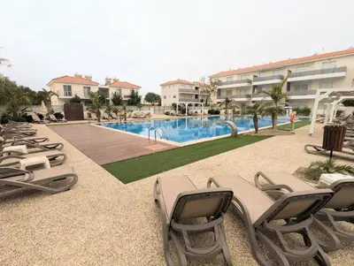 a row of lounge chairs next to a swimming pool at Violetta Apartment, Ground Floor Pool View in Paralimni