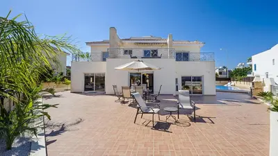 a patio with chairs and an umbrella in front of a house at Protaras Holiday Villa 196 in Protaras