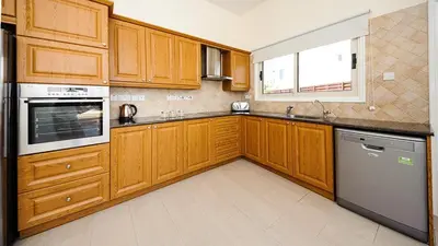 a kitchen with wooden cabinets and a sink and a dishwasher at Protaras Holiday Villa 196 in Protaras