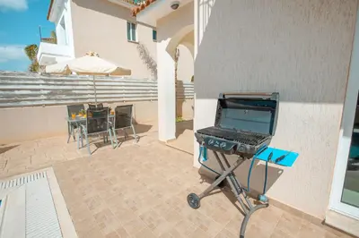 a barbecue grill on a patio with a table at Pernera Holiday Villa 173 in Protaras
