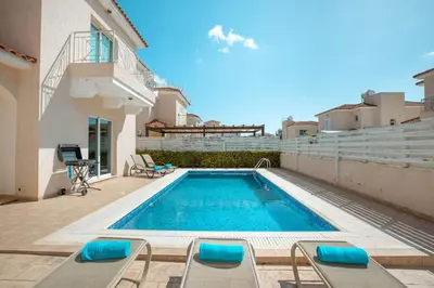 a swimming pool with lounge chairs next to a building at Pernera Holiday Villa 173 in Protaras