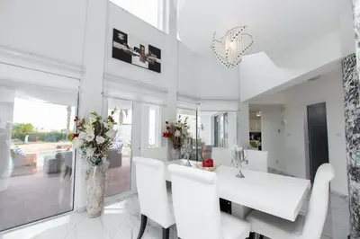 a white dining room with white chairs and a table at Protaras Holiday Villa 113 in Protaras