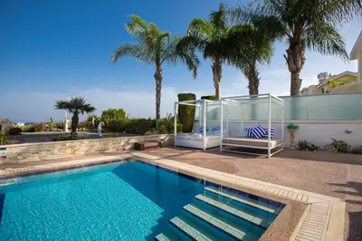 a swimming pool with palm trees and a house at Protaras Holiday Villa 113 in Protaras