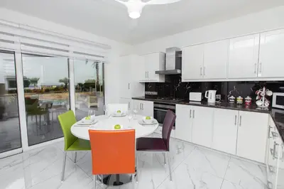 a white kitchen with a table and chairs at Protaras Holiday Villa 113 in Protaras