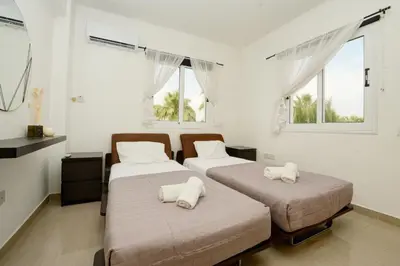 two beds in a room with two windows at Villa Thetida in Ayia Napa