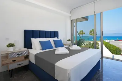 a bedroom with a large bed with a view of the ocean at Jenny - Beachfront Apartment in Protaras