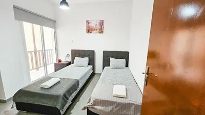 two twin beds in a room with a door at Heaven City Apartment, 150m from Chabad Lubavitch in Larnaka