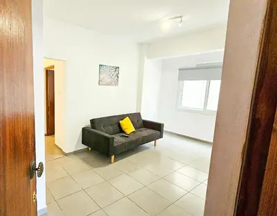 a living room with a black couch with a yellow pillow at Heaven City Apartment, 150m from Chabad Lubavitch in Larnaka