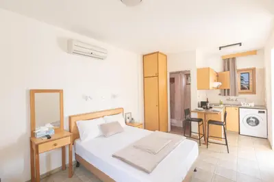 a bedroom with a white bed and a kitchen at Pernera Nest in Protaras