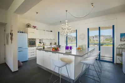 a kitchen with white cabinets and a large island with bar stools at Protaras Aster Seaside Suite in Protaras