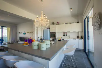 a kitchen with a large island with white cabinets and a chandelier at Protaras Aster Seaside Suite in Protaras