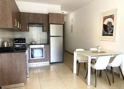a kitchen with a white table and white chairs at DPSAE09 Mythical Sands Resort - Two Bedroom Apt with pool in Paralimni
