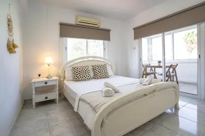 a bedroom with a white bed and a table at Large apartment close to Finikoudes Beach with 2 balconies in Larnaka