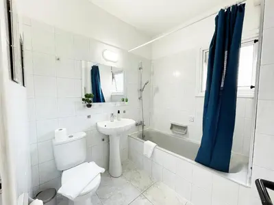 a white bathroom with a toilet and a sink at Large apartment close to Finikoudes Beach with 2 balconies in Larnaka