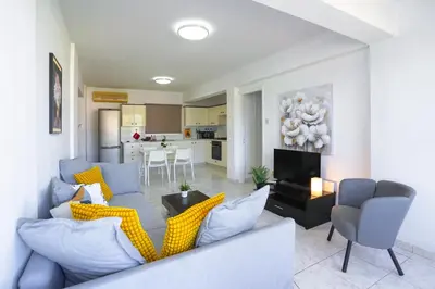 a living room with a couch and chairs and a kitchen at Large apartment close to Finikoudes Beach with 2 balconies in Larnaka