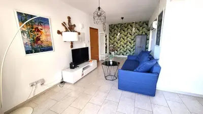 a living room with a blue couch and a tv at Beach Haven: 7-Minute walk to the beach + Pool in Larnaka