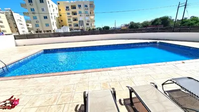 a swimming pool with chairs next to a building at Beach Haven: 7-Minute walk to the beach + Pool in Larnaka
