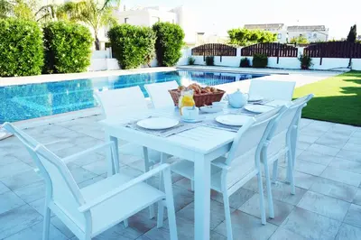a white table and chairs next to a pool at Villa Aquamarine in Ayia Napa