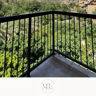 a balcony with a black railing with a view of a field at Maryland River Liz in Kakopetria
