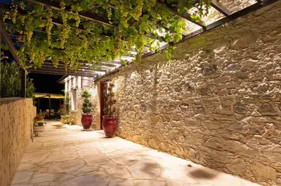 a stone wall with a pergola with potted plants at No 1 Mandria in Limassol