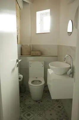 a white bathroom with a toilet and a sink at Little Stone House in Lymbia