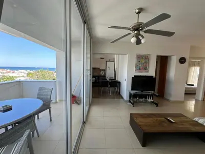 a living room with a ceiling fan and a table at Superb Seaview Flat, Prime Area in Larnaka