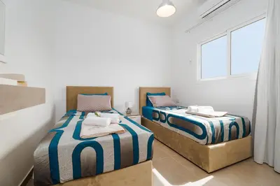 two twin beds in a room with a window at SunnyVillas 1 Bedroom Central Protaras in Protaras