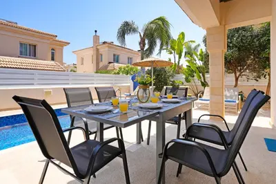 a table and chairs on a patio next to a pool at Villa Angelina - 300m from Kapparis beach in Paralimni