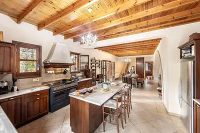 a kitchen with wooden ceilings and a table with chairs at Troodos Mature Pine Chalet in Pedoulas