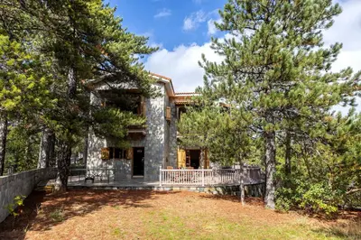 a large stone house with trees in front of it at Troodos Mature Pine Chalet in Pedoulas