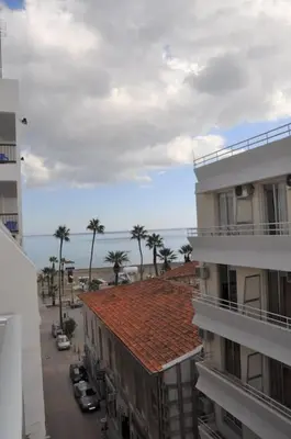 a city street with buildings and palm trees and the ocean at Liliana Sea View Suite in Larnaka