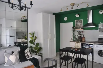 a kitchen and living room with green walls and a table at Aria Sea View Studio in Larnaka