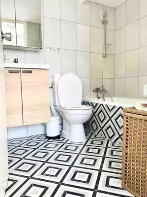 a bathroom with a toilet and a black and white tile floor at Emma Sea View Suite in Larnaka