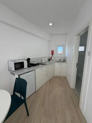 a kitchen with white cabinets and a table and a chair at Kitieos Central Apts 100m from Finikoudes Beach in Larnaka