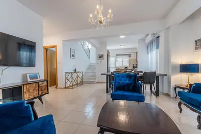 a living room with blue chairs and a table at Seaview Sanctuary House in Larnaka