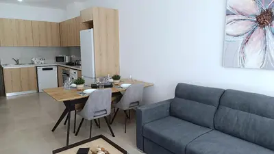 a living room with a couch and a table and a kitchen at Larvella Estia Luxury Suites in Larnaka