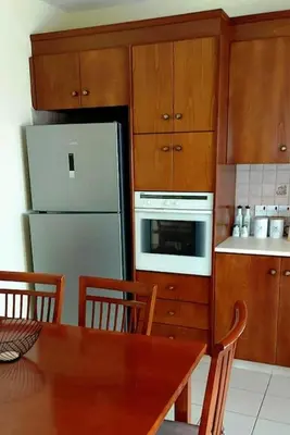 a kitchen with a wooden table and a white refrigerator at Balcony Sea View Whole Apt, Minutes To Beach in Limassol